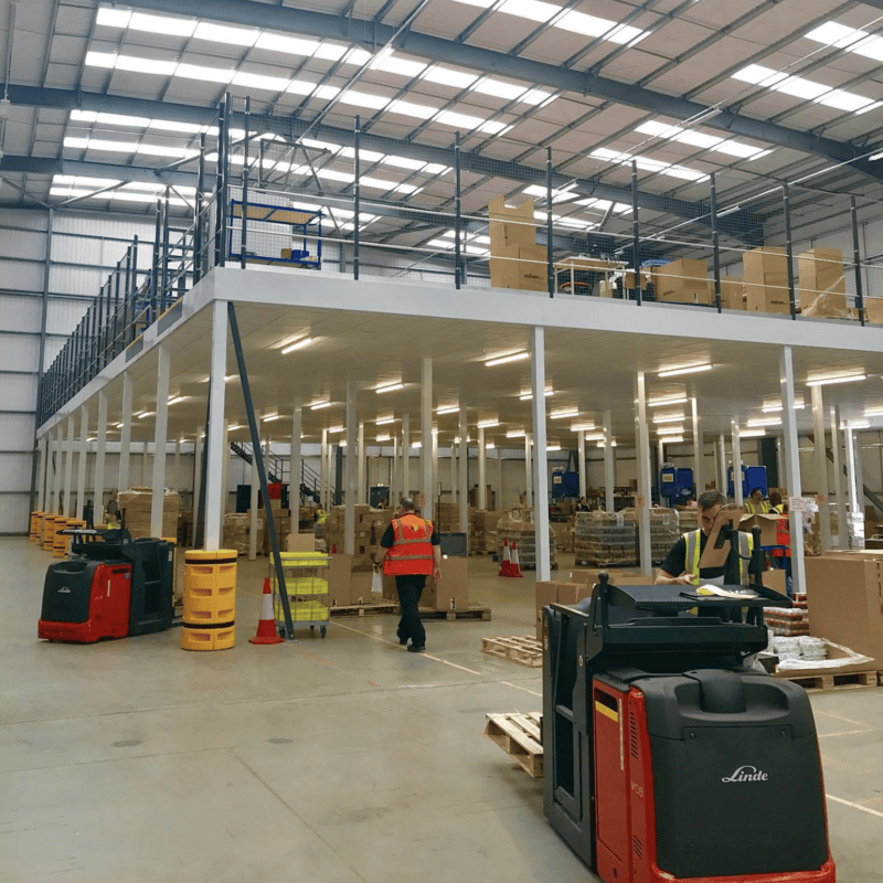 A large commercial property with a person walking in a high-vis jacket and a small forklift truck in the foreground.