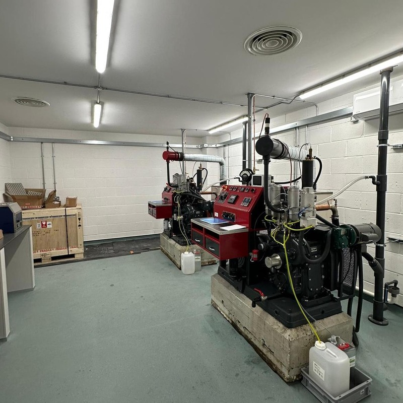A room in an industrial facility with strip lighting and several large machines.