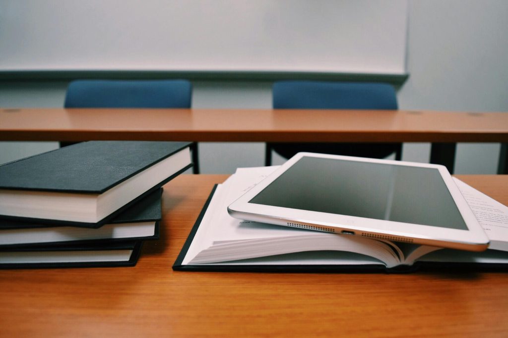 Stack of educational books on a classroom table, symbolising the importance of electricians in supporting safe and effective learning spaces through reliable electrical systems.
